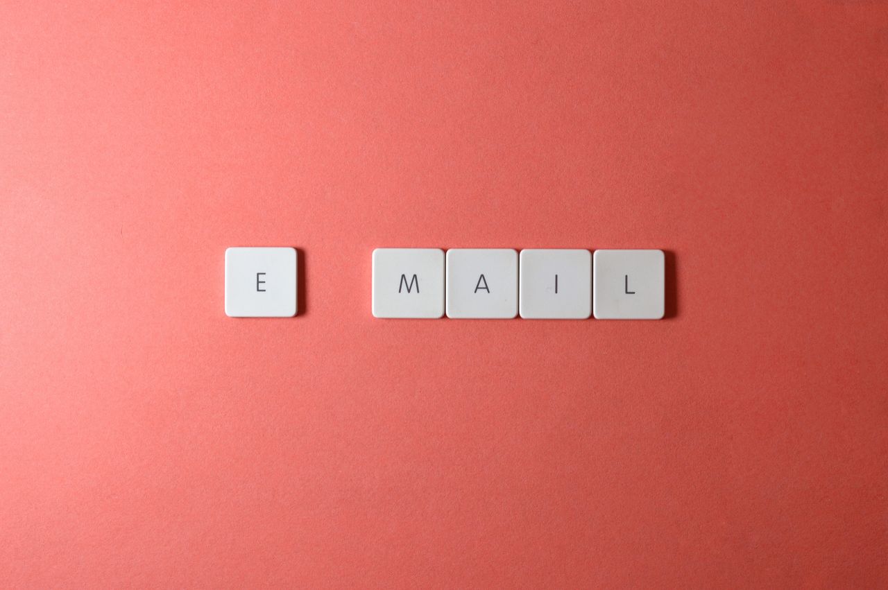 Vue en plongée de lettres sur clavier formant le mot email sur un fond corail.